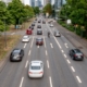 Mehrspurige Stadtstraße mit deutlichen Fahrbahnmarkierungen, Ampeln und fließendem Verkehr – Straßenmarkierung sorgt für bessere Orientierung.