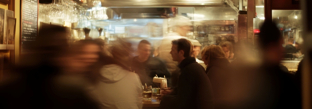 Verschommenes Bild von Menschen, die nachts in einem geschäftigen Restaurant essen.