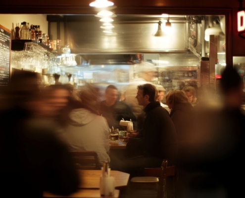 Verschommenes Bild von Menschen, die nachts in einem geschäftigen Restaurant essen.