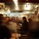 Verschommenes Bild von Menschen, die nachts in einem geschäftigen Restaurant essen.