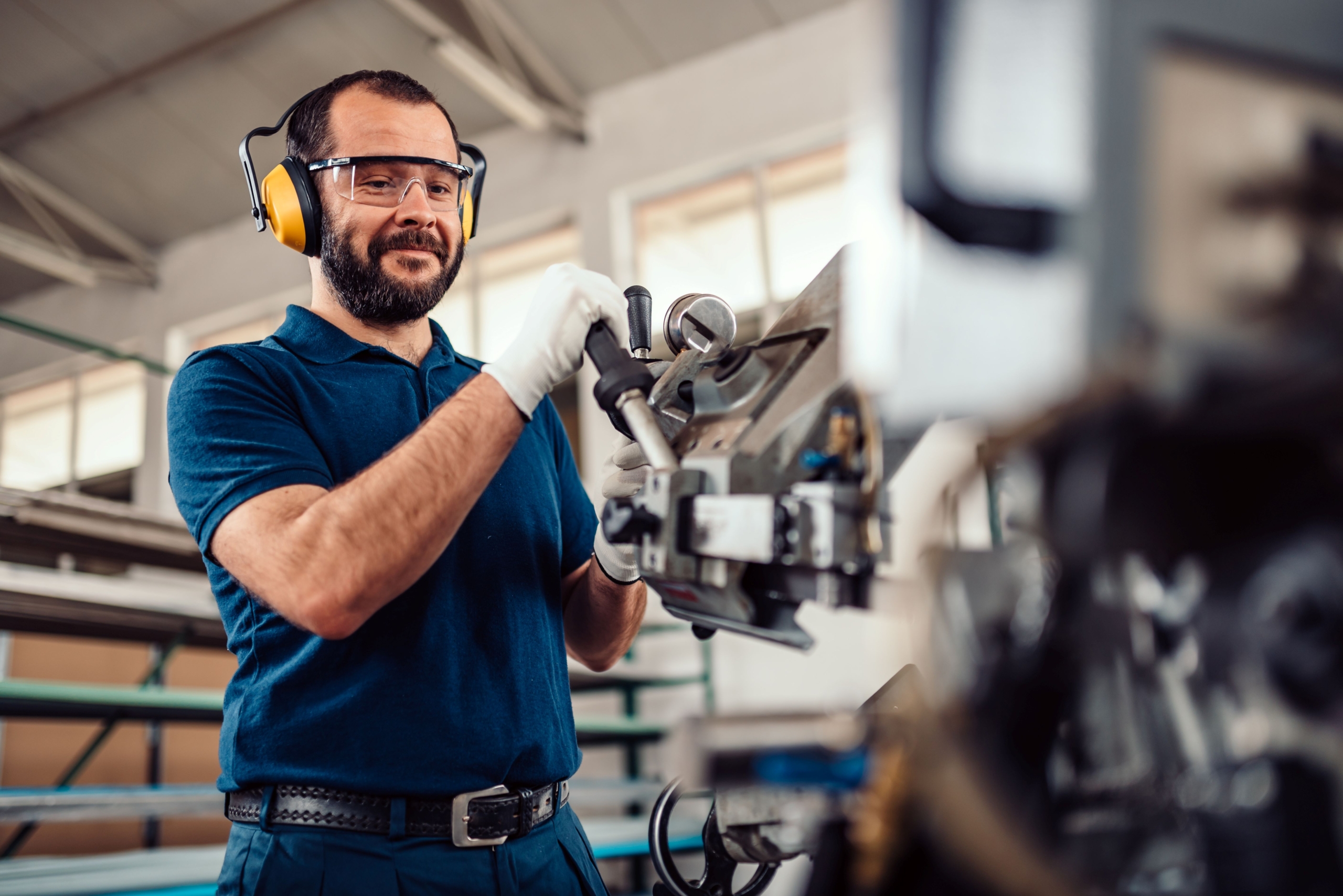 Arbeiter mit Schutzausrüstung bedient eine Maschine