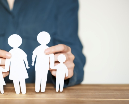 Papierausschnitt einer vierkoepfigen Familie auf Holztisch – Symbolbild fuer geteiltes Sorgerecht und moderne Familienmodelle