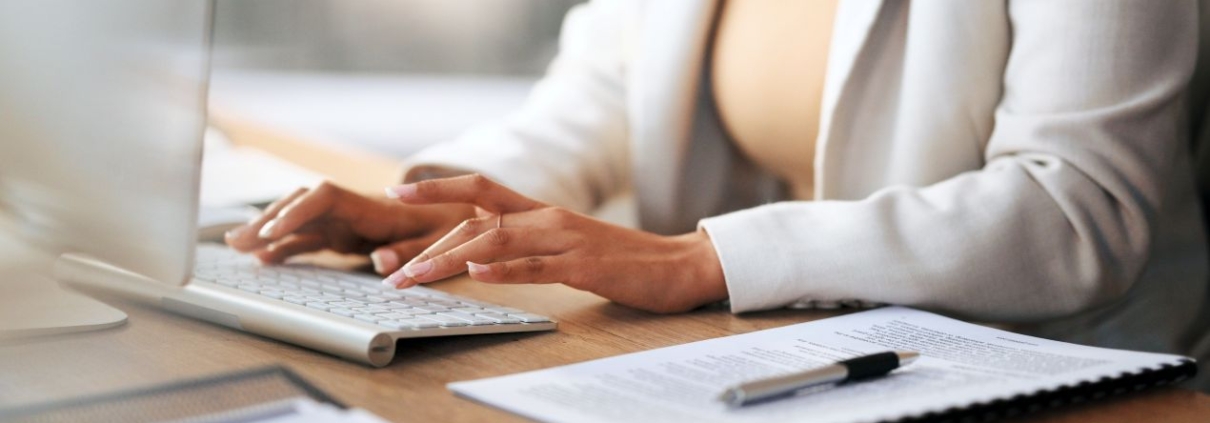 Frau arbeitet am Schreibtisch mit Tastatur und Dokumenten – Thema: Bueroservice Preise und Arbeitsentlastung im Backoffice