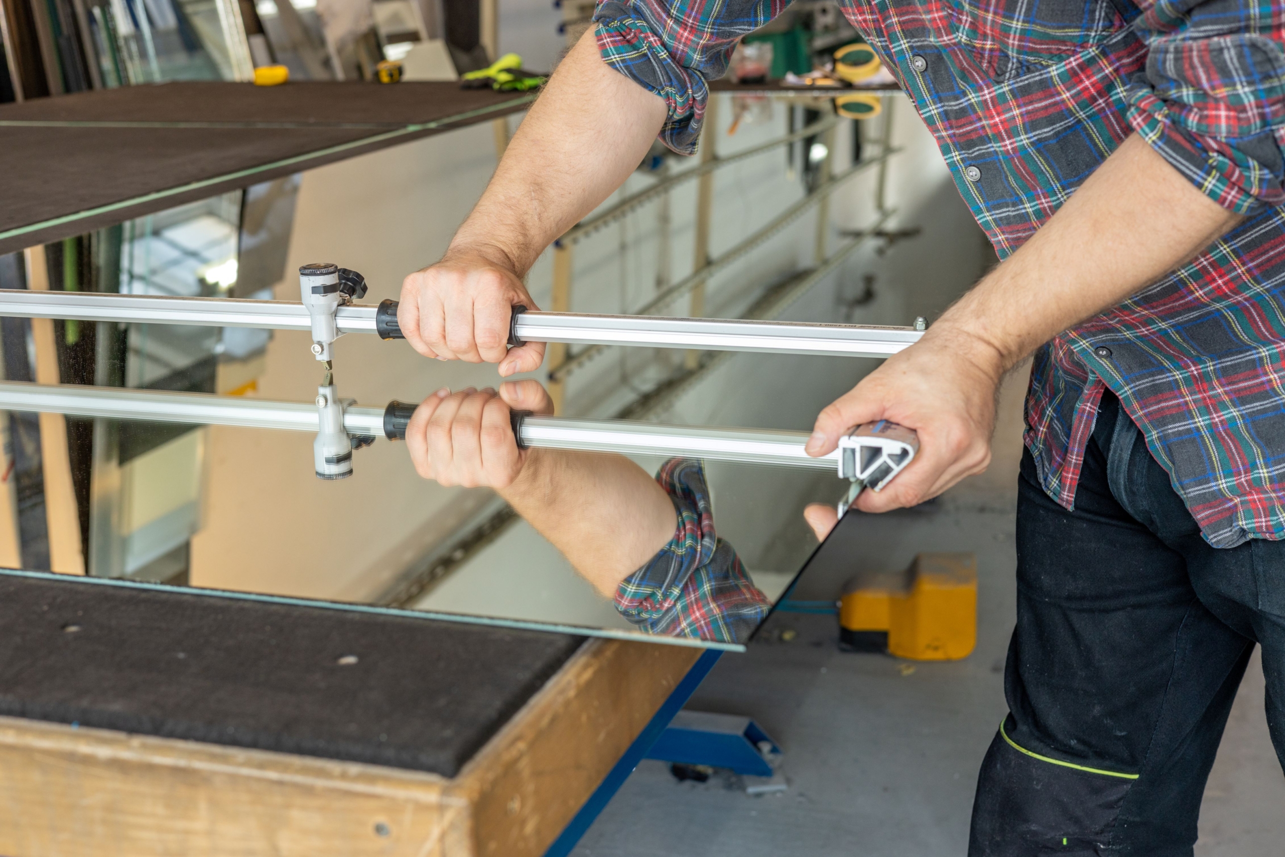 Handwerker richtet Fensterglas mit Spezialwerkzeug aus – Symbol für Qualitätskontrolle beim Fensterbauer