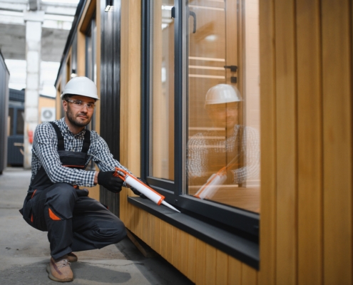 Arbeiter montiert Fenster an modularer Hallenbüro Konstruktion in Industriehalle
